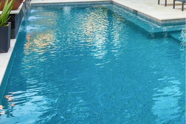 A recently repaired pool with fire bowls along the side of it