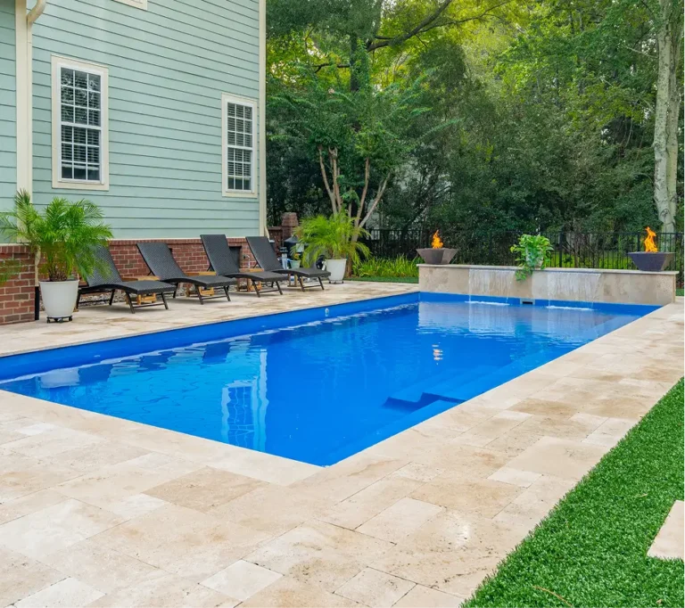 Full backyard pool remodel by Legacy Pools featuring a new stone patio, lounge area, and a waterfall wall with integrated fire bowls.