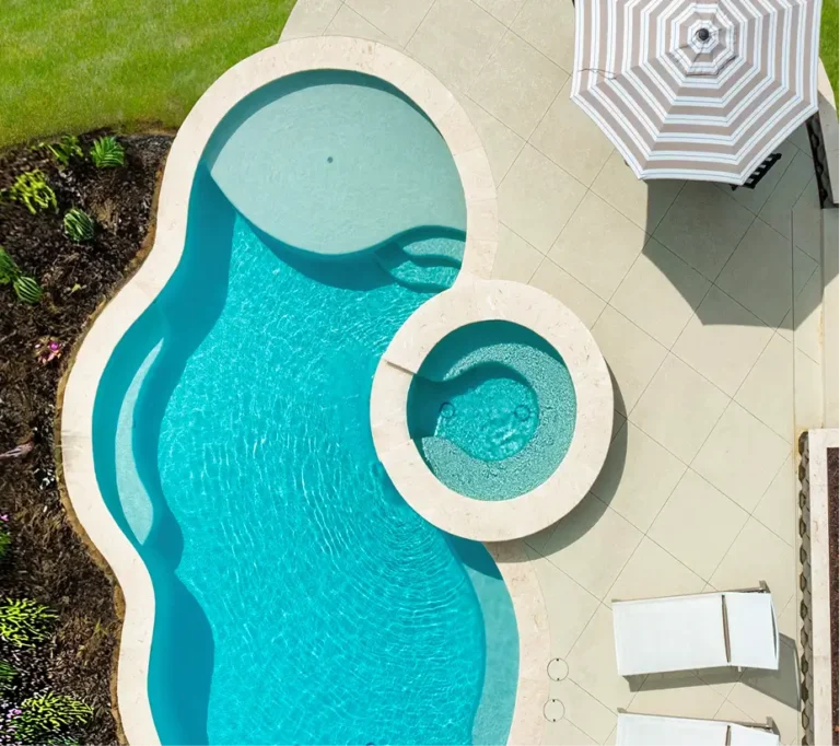Birds-eye view of a custom-shaped pool upgrade by Legacy Pools featuring a circular spillover spa and a wide tanning ledge.