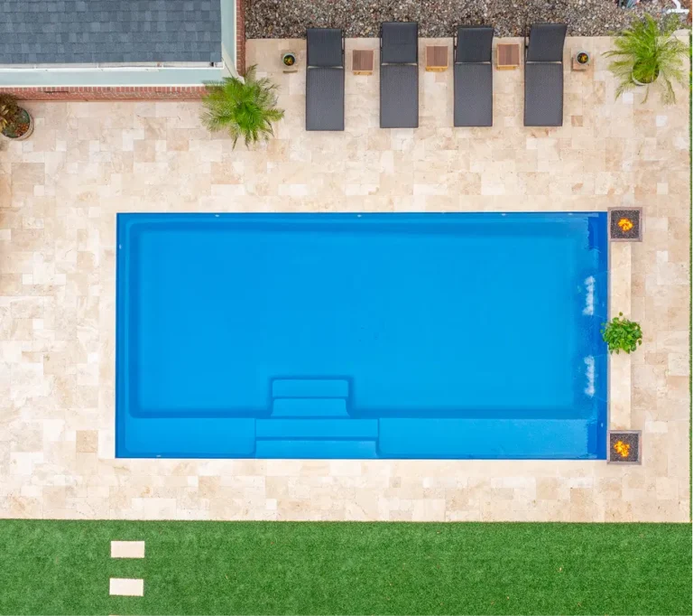 Top-down view of a rectangular pool renovation by Legacy Pools with light stone pavers, lounge seating, and integrated fire pits.