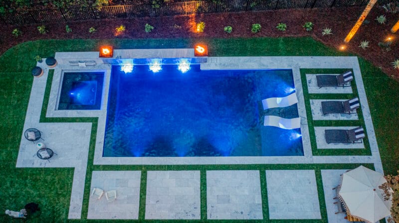 An aerial view of a gunite pool in a backyard at night