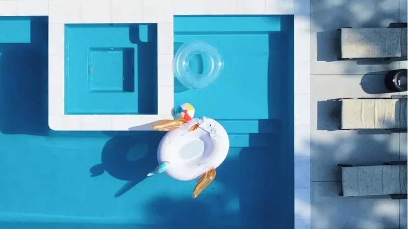 Aerial view of a modern swimming pool remodel by Legacy Pools featuring a built-in spa, tanning ledge, and vibrant blue water