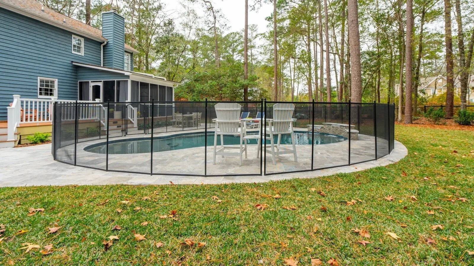 Modern backyard swimming pool with clear blue water, surrounding patio, and landscaped outdoor living area.