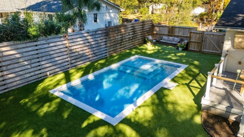 A rectangular pool covered in shadows during the day time