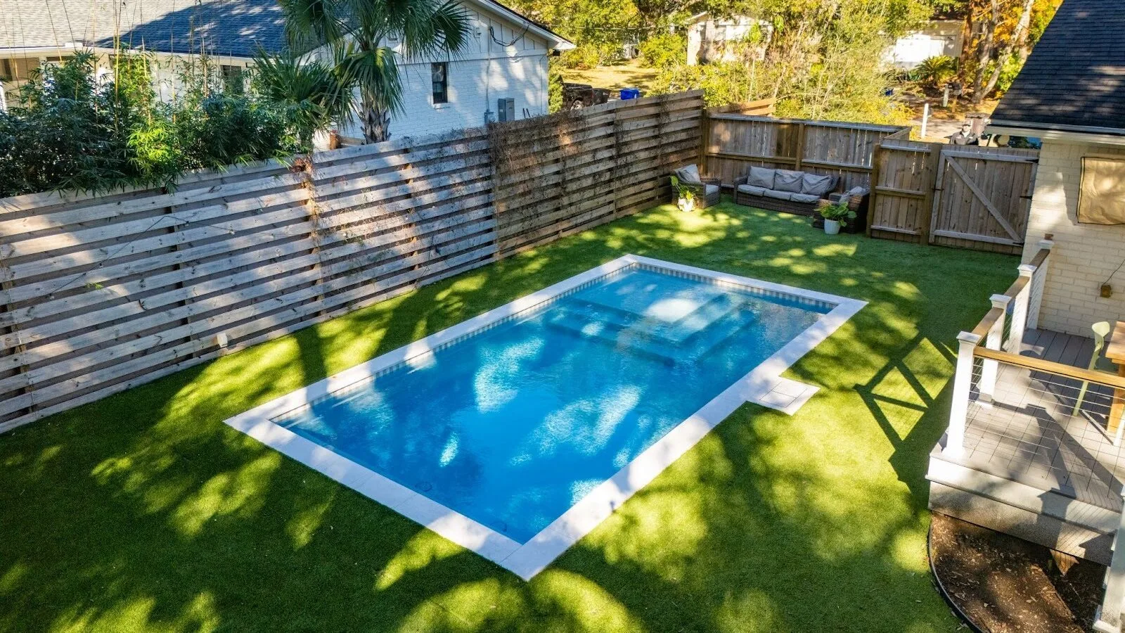 A rectangular pool covered in shadows during the day time