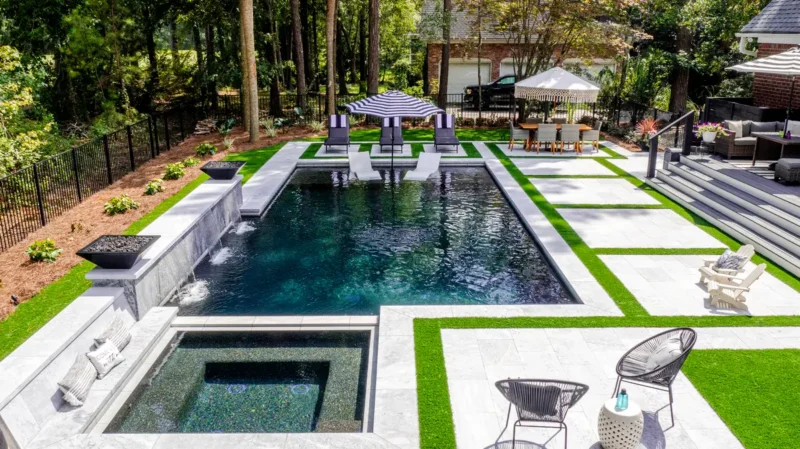 Pool with dark tile waterfall wall and built-in planter.
