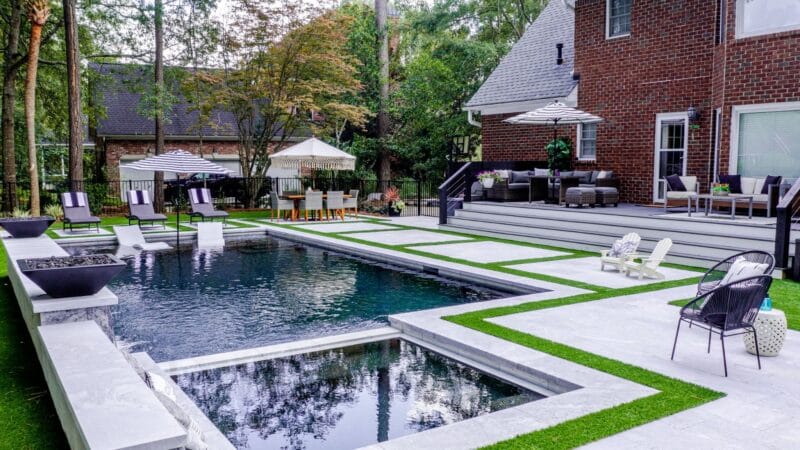 A square gunite pool behind a brick house