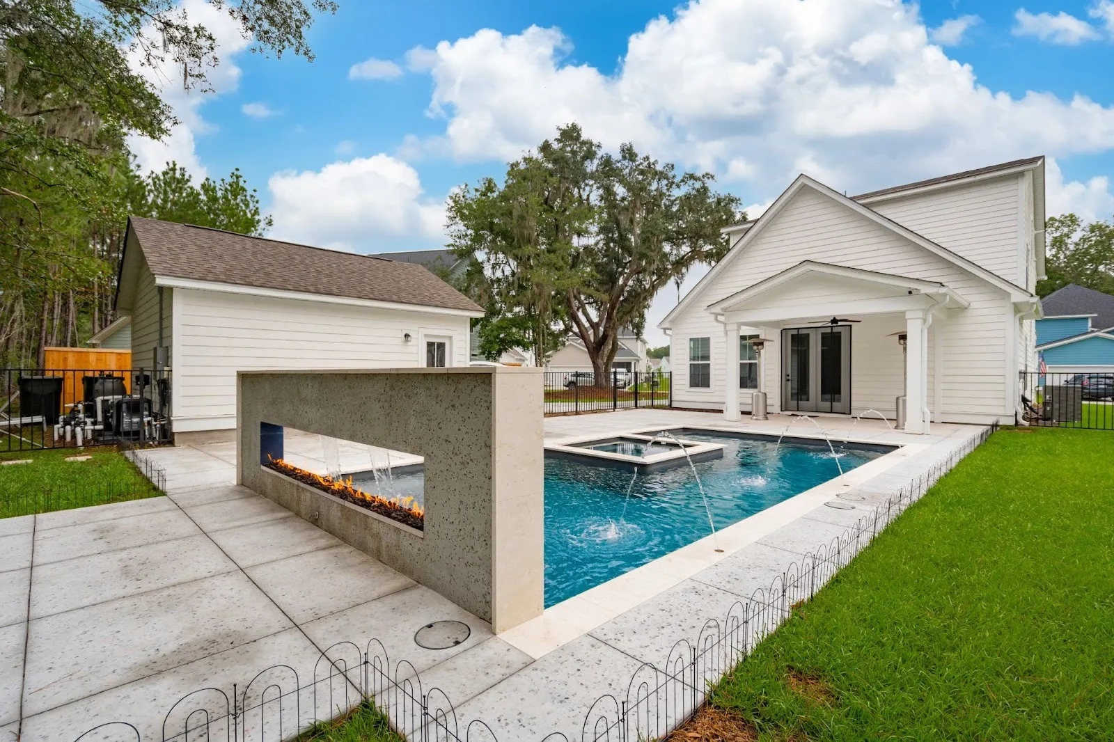A rectangular gunite pool in a backyard with a large wall at one end of the pool