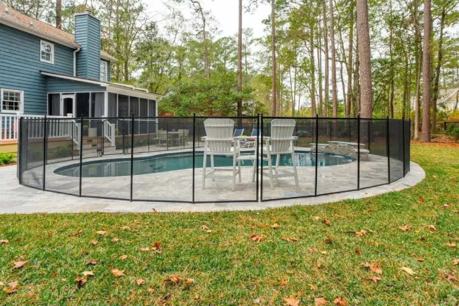 Modern backyard swimming pool with clear blue water, surrounding patio, and landscaped outdoor living area.