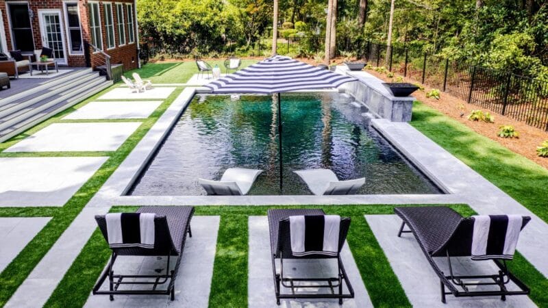 A country club-style gunite pool with umbrella and lounge chairs