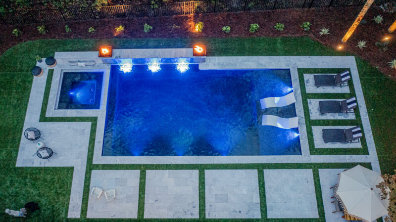 An aerial view of a gunite pool in a backyard at night