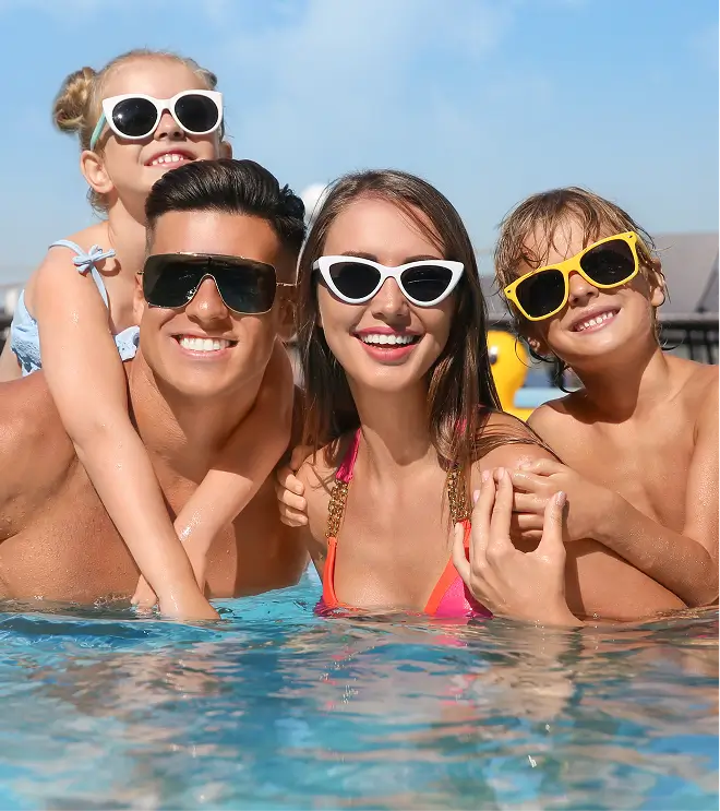 Family of four smiling in a swimming pool.
