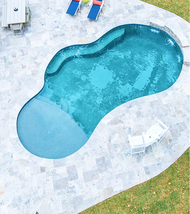 Aerial view of a freeform pool with travertine deck and lounge chairs.