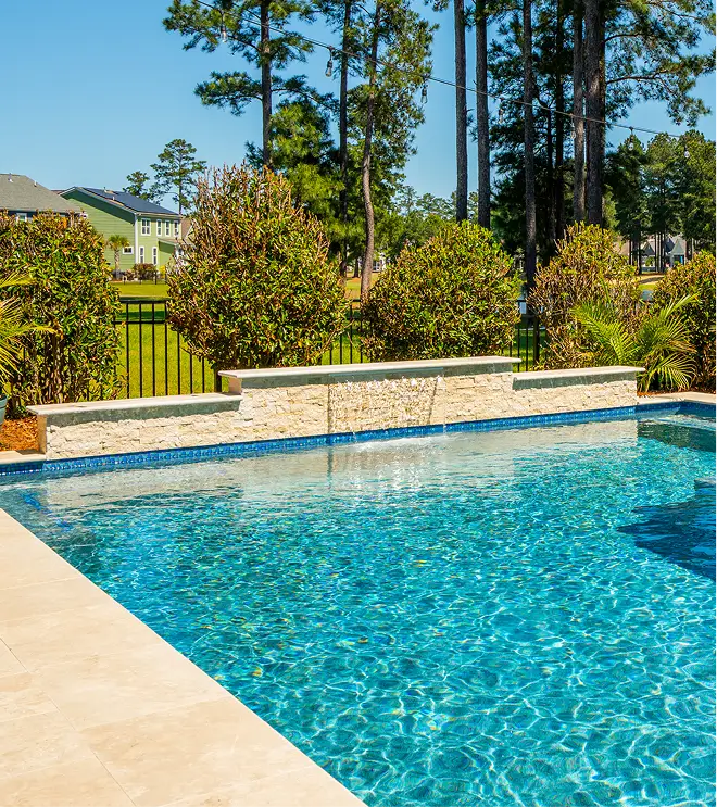 Modern geometric pool with stone waterfall wall and blue tile accent.