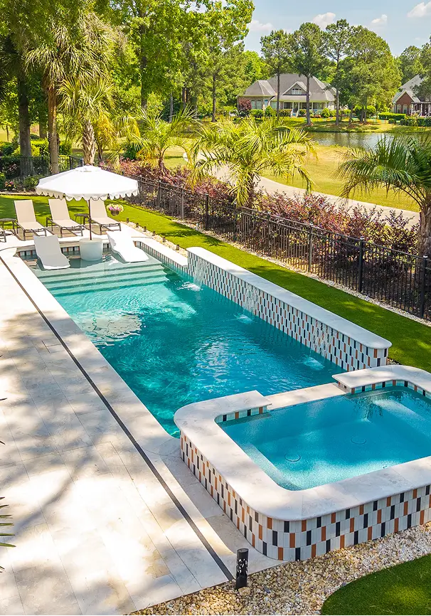 Custom pool with mosaic tile border, spa, and sun shelf with umbrella.