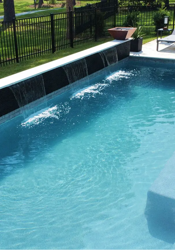 Pool with dark tile waterfall wall and built-in planter.