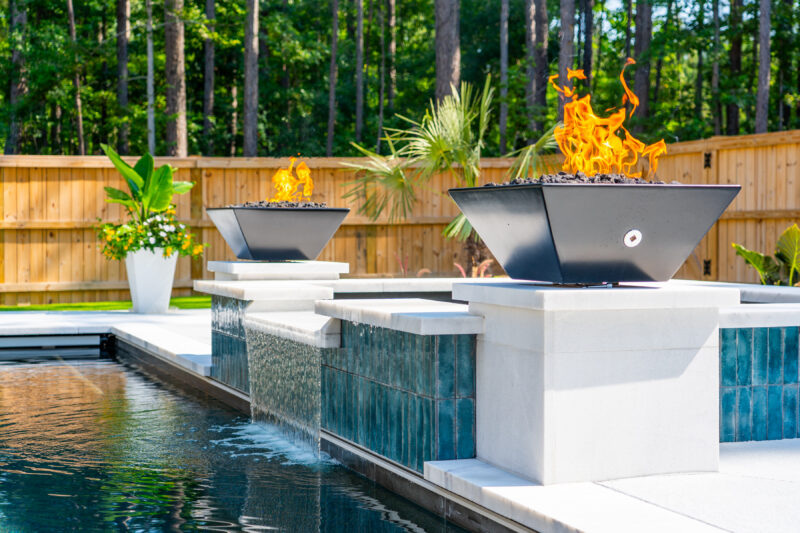 A gunite pool with copper fire bowls on display
