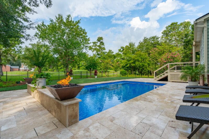 Fiberglass pool with copper fire bowls on one end of the pool