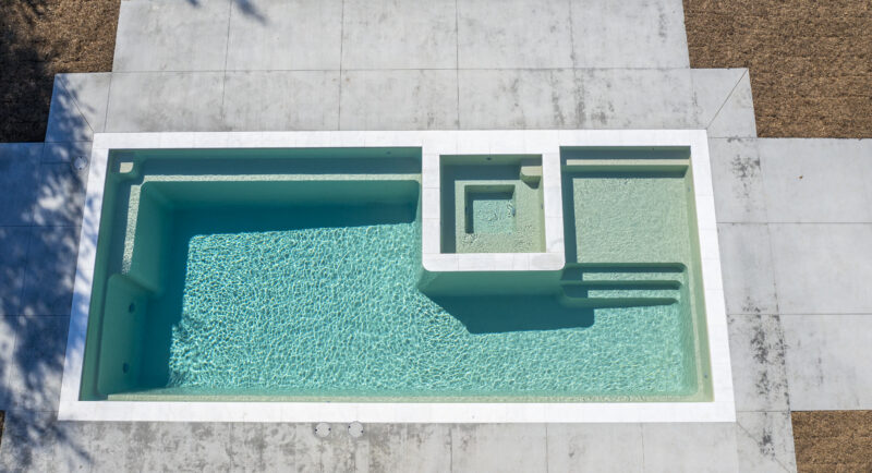 A picture of a fiberglass pool near a stone deck