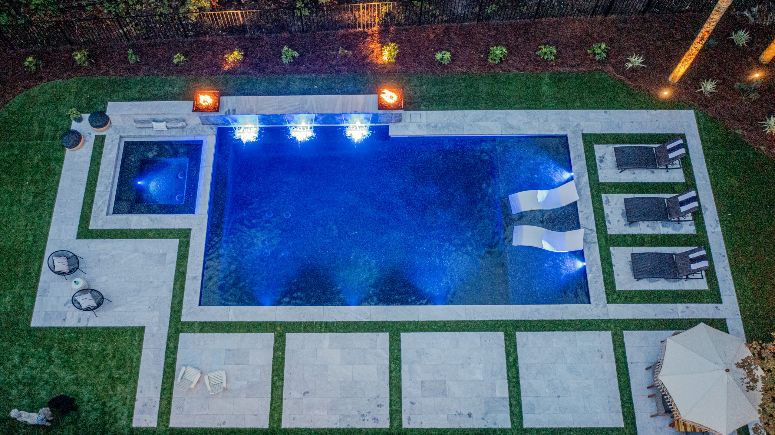 An aerial view of a gunite pool in a backyard at night