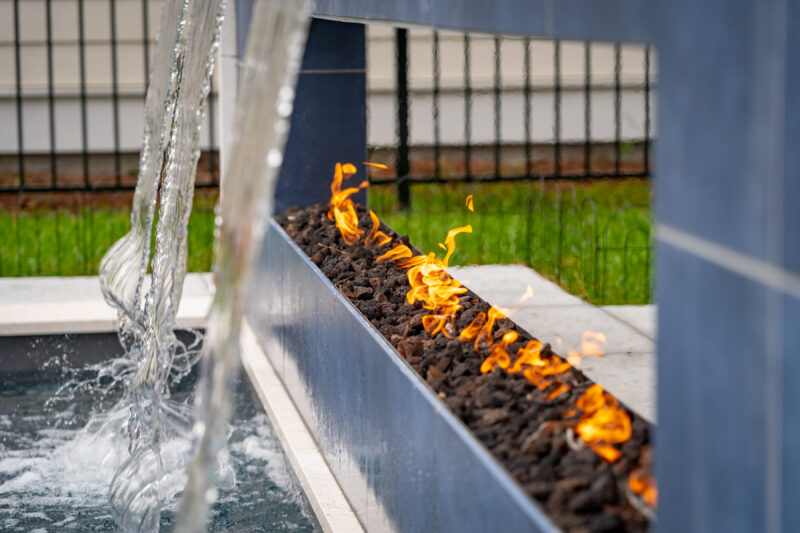 Waterfall cascades and a fire pit scaled around a backyard swimming pool