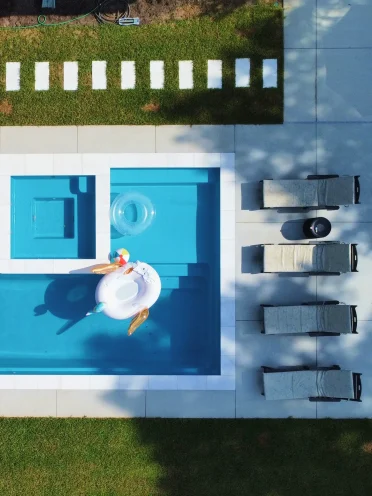 Overhead view of a modern custom geometric inground pool with an adjacent square spa, minimalist grey stone pavers by Legacy Pools.